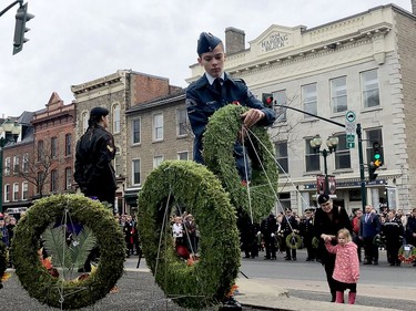 Air Cadet Cpl. Rogan Cozens, of 870 Vampire Squadron, lays a wreath at the Brockville cenotaph for navy veteran Kate McKinnon, right, who watches with her daughter Hannah, while Cpl. Audrey Henry, of the 113th Royal Canadian Army Cadet Corps, stands at attention to the left. (RONALD ZAJAC/The Recorder and Times)