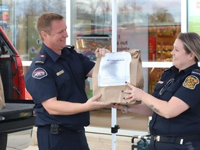 Prescott firefighter John Gibson is handed a bag of non-perishables by Edwardsburgh Cardinal firefighter Erika MacDonald in front of O'Reilly's Your Independent Grocer on Saturday. The Augusta Fire Department also took part in the Fill the Fire Truck event that collected food and money for the Spirit of Giving campaign in the South Grenville area.
Tim Ruhnke/Postmedia Network