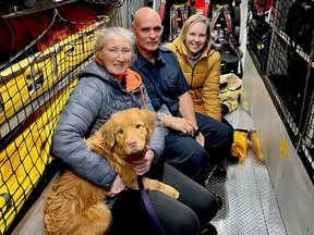 Helen Cooper holds Flanker after rescuing him from the St. Lawrence River on Wednesday night, as they warm up inside a fire truck with Fire Capt. Craig Mason and Flanker's owner, Chelsea Marko. (SUBMITTED PHOTO)