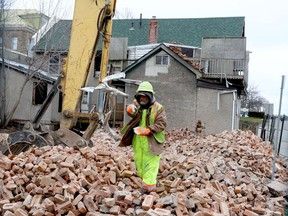 Larry Sullivan, of Fast Eddie's, discards a metal object as a colleague clears debris from the demolition site at the corner of Market Street West and Water Street, while the Black-Earle Double House looms in the background, on Monday afternoon. (RONALD ZAJAC/The Recorder and Times)
