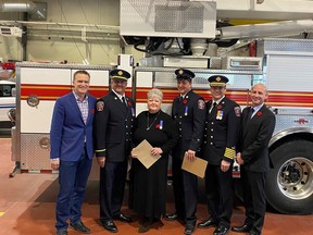 Honourable Minister Peter Guthrie, fire prevention officer Jay Wieliczko, administrative assistant Dot Gillis, senior fire fighter Joe Zelmer, Chief Shawn A.C. Polley, and Mayor Jeff Genung pose at the fire hall in Cochrane. Not pictured: Mike Monaghan, 1st Class Firefighter.