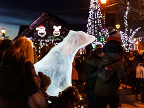 People stand around a polar bear sculpture at Light Up in Historic Downtown Cochrane on Saturday, Nov. 26, 2022.