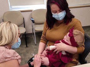 Red Deer mom Abby Ward holds baby Mavis for her flu immunization on October 17. AHS photo