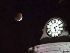 The moon slides into the Earth's shadow next to the clock tower at Kingston City Hall during the total lunar eclipse as it was seen from Kingston on Tuesday.