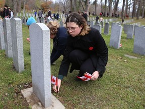 La Salle Intermediate and Secondary School Grade 7 pupil Anna Hohertz places a flag on a war grave at Cataraqui Cemetery during the Day of Remembrance Ceremony on Thursday.