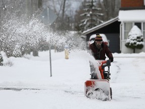 A Napanee resident clears his driveway following the first snowfall of the day on Saturday morning. More snow is expected throughout the day.