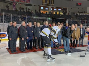 Mark Major drops the ceremonial puck, standing with 27 other alumni, during the Canadians and Raiders Night at the Kingston Frontenacs' home game against the Sudbury Wolves at the Leon's Centre in Kingston, Ont., on Friday, Nov. 25, 2022. The franchise is celebrating 50 years of major junior hockey in Kingston.
