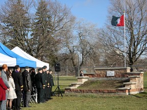 Attendees watch the raising of the Canadian Military’s Intelligence Branch flag over the monument unveiled for Maj.-Gen. Reg Weeks, during a ceremony at Canadian Forces Base Kingston on Saturday.