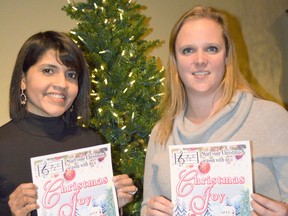 Anusha Arulnathi, left, and Shelley Roberts display the choir's Christmas concert poster that has been distributed throughout the area to publicize the event.  They both sing in the alto section and will be part of a small ensemble featured in one of the beautiful Christmas songs at the December 4th concert.