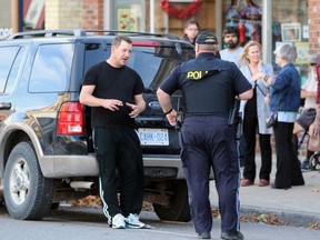 A Lambton OPP officer talks to a man leaning against a Ford Explorer following a collision on Saturday in Petrolia. Terry Bridge/Sarnia Observer/Postmedia Network