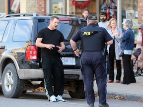 A Lambton OPP officer talks to a man leaning against a Ford Explorer following a collision on Saturday in Petrolia.  Terry Bridge/Sarnia Observer/Postmedia Network