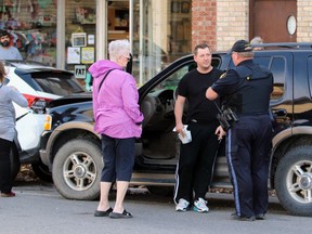 A Lambton OPP officer talks to a man leaning against a Ford Explorer following a collision on Saturday in Petrolia.  Terry Bridge/Sarnia Observer/Postmedia Network