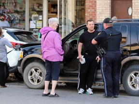 A Lambton OPP officer talks to a man leaning against a Ford Explorer following a collision on Saturday in Petrolia. Terry Bridge/Sarnia Observer/Postmedia Network