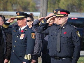 Sarnia Fire Chief Bryan Van Gaver, left, and Police Chief Derek Davis salute during Thursday's Remembrance Day service at the Aamjiwnaang First Nation in Sarnia.