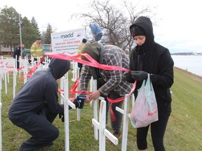 Cara Mathieson gets ribbons ready to be stapled to the MADD Sarnia-Lambton white cross display Saturday on the St. Clair Parkway.