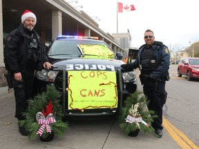 Sarnia police Const. Reg Musclow, left, and Const. Mike Ross collect donations of non-perishable food from the public during last year's Cops for Cans food drive.