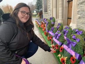 Whitney Wilson of Straffordville places a poppy by a wreath at the Norfolk War Memorial Carillon Tower following Friday's Remembrance Day ceremony. VINCENT BALL