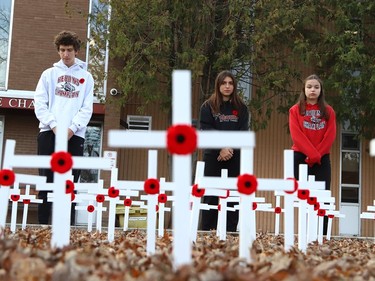Tyler Roney, left, Addison Bergeron and Reija Dellaire stand in silence in front of hundreds of crosses placed in front of Ecole secondaire catholique Champlain in Chelmsford, Ont. on Friday November 11, 2022. Each student at the school took their turn standing at the crosses. The event was held to mark Remembrance Day. John Lappa/Sudbury Star/Postmedia Network