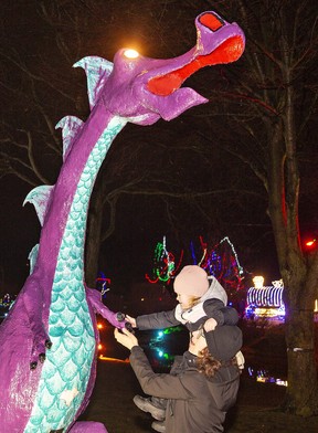 Brooke Hoskins of Barrie gives her three-year-old daughter Emery a boost so she can touch the paw of a dragon at the Simcoe Panorama in Wellington Park on New Year's Eve.  Brian Thompson/Postmedia Network
