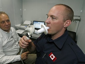 Strathcona County firefighter Jason Biggeman (right) blows into a spirometer to test his lung function after returning from fighting the forest fire near Fort McMurray, Alberta. Professor Jeremy Beach (left, Dept. of Medicine, University of Alberta) was part of a team conducting the tests on the firefighters in Sherwood Park on May 18, 2016. Larry Wong/Postmedia Network