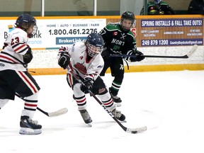 Ben Barriault (24) of the Copper Cliff Reds handles the puck while teammate Neven Brujic (23) battles for position and Hayden Horbul (87) of the Timmins North Stars defends during Sudbury Silver Stick U12 AA hockey tournament action at McClelland Arena in Copper Cliff, Ontario on Saturday, December 3, 2022.