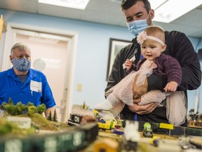 Paul Kulinek holds his 9-month-old daughter Everly Collins-Kulinek as a train passes by underneath her during a Christmas event on Saturday at the Belleville Model Railway Club. ALEX FILIPE
