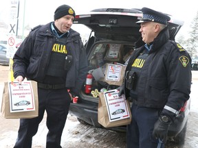 Const. Jeff Dewar and Staff Sgt. Ryan McLeod, members of Ontario Provincial Police Auxiliary, accept donations during their Stuff a Cruiser event at Rome's Your Independent Grocer on Saturday, Dec 17, 2022 in Sault Ste. Marie, Ont. Donations helped Soup Kitchen Community Centre. (BRIAN KELLY/THE SAULT STAR/POSTMEDIA NETWORK)