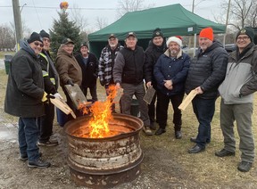 Members of the Waterford Lions Club add some wood to a fire they had going to help keep warm near the food truck set up at the end of the Santa Claus parade route at James Street South and Alice Street on Saturday.  The club organized the parade for the second time in as many years.  VINCENT BALL
