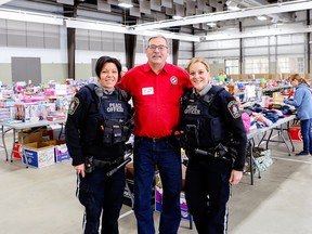 Stony Plain Peace Officers Veronica Wenzel (left) and Jennifer Penner (right) and Kinsmen Christmas Hampers Chair Ed Berney (centre) were among dozens of volunteers who helped build Christmas gift hampers for over 1,400 children in the Tri-Municipal Region last week at Heritage Park Pavilion. Photo courtesy of the Town of Stony Plain.