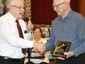 On behalf of the Mitchell Legion Band, Clare French (left) presents Art Heimpel with a plaque recognizing his longtime dedication to the band during their Christmas Concert held Dec. 6 at the Crystal Palace. The 86-year-old Heimpel played the trombone for more thn 50 years in the Legion Band, but was a member of the Mitchell Band in the 1950s. ANDY BADER/MITCHELL ADVOCATE