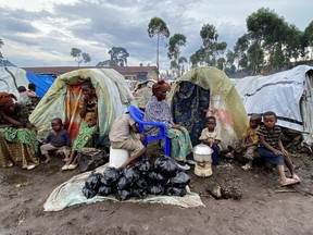 Paskazia Kimanuka 58, sits with her children outside their makeshift shelter at the Kanyaruchinya camp for the internally displaced people near Goma in the North Kivu province of the Democratic Republic of Congo on Nov. 22, 2022.