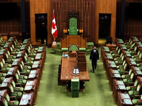 A page places calendars on the desks of Members of Parliament in the House of Commons in Ottawa