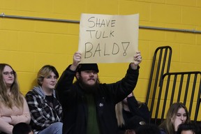 A student with a sign cheers for Dan Tulk getting shaved bald at Fort McMurray Composite School after $13,000 was raised for local charities on December 15, 2022. Photo by Momin Syed/FMPSD