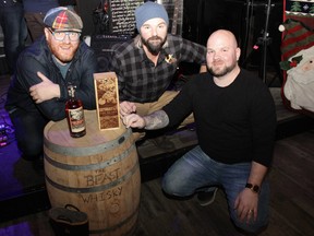 L-R: Distillers Bryce Parsons and Spike Baker with Fort McMurray firefighter Scott Germain with a bottle of The Beast whisky at Paddy McSwiggins in Fort McMurray on Saturday, December 3, 2022. The whisky is made from a pallet of peated malt that was left outside of the Wood Buffalo Brewing Company during the 2016 Horse River wildfire. Vincent McDermott/Fort McMurray Today/Postmedia Network