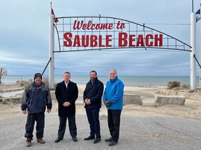 Left to right, Mayor Garry Michi, South Bruce Peninsula;  Chris Tsakopoulos, Vice President, Network Build at Xplore;  SWIFT Board Member and Saugeen Shores Mayor Luke Charbonneau and Bruce-Grey-Owen Sound MPP Rick Byers pose under the Sauble Beach sign.  Photo submitted.
