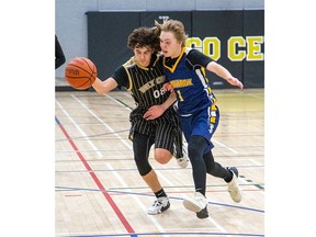 Jackson Mooney of the Holy Cross Centurions is fouled by Strathroy Saint Ben Fowler during a junior boys TVRA basketball game at Holy Cross in Strathroy on Wednesday, Dec. 14, 2022. The Saints won 50-48. (Derek Ruttan/The London Free Press)