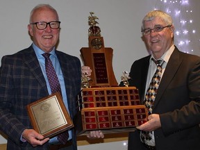 Peter McCabe, left, holds his keeper trophy and helps support
the massive trophy awarded annually over many years for Barbershopper of the Year, chosen by secret ballot by a majority of members. Presenting the award is Ray Doyle, right, show chair for the barbershop chorus and last previous recipient of the award. JACK EVANS PHOTO