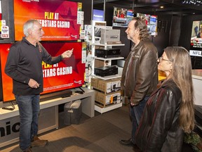 Howie Fraser (left) of FM Audio Video on King George Road explains the features of some televisions to Steve Burchell and Kathy Phillips of Brantford on Boxing Day.