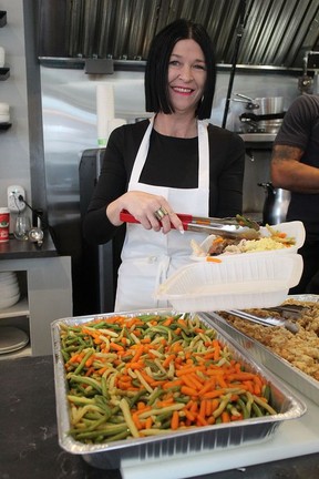 Tammy Hunt dishes up vegetables that were part of a traditional holiday meal provided to the community for free at Honey's Bistro on Christmas Day.  MICHAEL RUBY