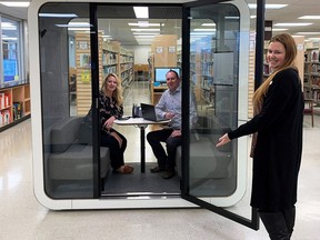 Tiffany Gartner-Duff, engagement and partnerships specialist with Chatham-Kent Ontario Health Team, and Matt Keech, program manager for Chatham-Kent Employment and Social Services, sit inside a new quiet pod at the Chatham-Kent Public Library as Cassey Beauvais, manager of public services for the Chatham-Kent Public Library holds open the door. (Handout/Postmedia Network)