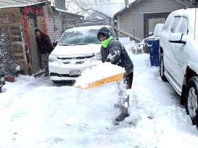 Ann Quenneville was working hard to finish off shovelling the driveway so her husband Kevin, seen in back, could get to work on Friday during a winter storm that hit the region.  PHOTO Ellwood Shreve/Chatham Daily News