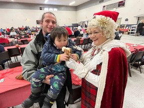 Mrs. Claus was in attendance at the turkey dinner lunch at the Agora Centre, and she had a present for Gustav Seguin-Wilkins, with dad Tristen Wilkins. Photo on Sunday, December 25, 2022, in Cornwall, Ont. Todd Hambleton/Cornwall Standard-Freeholder/Postmedia Network