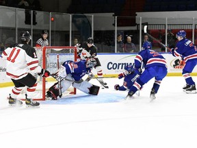 Foto: Roberts Lefebvre/Hockey Canada Vārtsargs Kristians Manness skatās Kanādas Vesta Liamu Votkinsu Junior World Challenge laikā Kornvolas pilsētvides kompleksā svētdien, 2022. gada 11. decembrī. Kanādas rietumi uzvarēja ar 5:3.