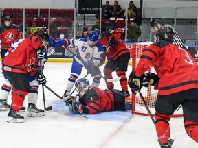 Roberts Lefevrs/Hockey Canada Pictures Austrumkanādas vārtsargs Čezs Niksons nosmacē ASV spēlētāja Raiena Sentluisas ripu Pasaules Junioru izaicinājuma spēlē Kornvolas pilsētvides kompleksā trešdien, 2022. gada 14. decembrī. ASV uzvarēja ar 7:2.