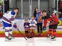 Robert Lefebvre/Hockey Canada Images Cornwall Royals alumnus Dave Ezard's daughter Kristen, with her children, drops the ceremonial faceoff puck for Canada East captain Trent Crane, right, and USA captain Cole Knuble at the World Junior A Challenge at the Cornwall Civic Complex on Wednesday, December 14, 2022;  they were invited when it was announced that Ezard will be inducted into the QJMHL hall of fame in 2023.