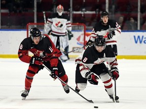 Roberts Lefevrs/Hockey Canada Images, Kanādas Austrumu spēlētājs Semjuels Asinivejs pa kreisi un Kanādas Rietumu spēlētājs Briks Makkinlijs dzenas pēc ripas World Jr. Challenge laikā. Pirmdien, 2022. gada 12. decembrī, Kornvolas pilsētvides kompleksā A. Kanādas rietumi šajā spēlē uzvarēja ar 6:3.