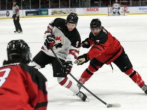 Roberts Lefevrs/Hockey Canada foto Hadsons Malinovskis no Kanādas rietumiem, pa kreisi, ņem momentu, kad Kanādas austrumu spēlētājs Raiens Džonstons izdara spiedienu World Jr. Challenge laikā.  A Kornvolas pilsētvides kompleksā pirmdien, 2022. gada 12. decembrī. Kanādas rietumi uzvarēja 6. spēlē. 3.