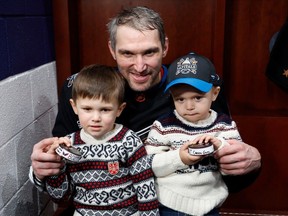 Dec 23, 2022: Washington Capitals' Alex Ovechkin in the locker room with sons Sergei (L) and Ilya (R), holding the pucks from his 801st and 802nd career goals after the Capitals' game against the Winnipeg Jets. Those goals moved him into second place all-time in career NHL goals, passing the late Gordie Howe.