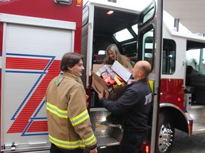Unloading donated toys from a Point Edward fire truck are, from left, firefighters Gavin Burgess, Justine Davies and Claudio Palleschi.  The toys were delivered Friday to Bluewater Health.  (PAUL MORDEN/The Observer)