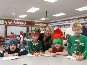 Pupils at Rosedale public school in Sarnia fill in Christmas cards for this year's Lambton Elderly Outreach Christmas gift program. It is distributing gift packages to 90 clients of the agency this week. From left, pupils in a Grade 2 class at Rosedale, Sam Prescott, 7, Alexis Chesher, 7, Wren Sandiland, 7, and Nash Chartrand, 7. With them is Amy Weiler with Lambton Elderly Outreach.